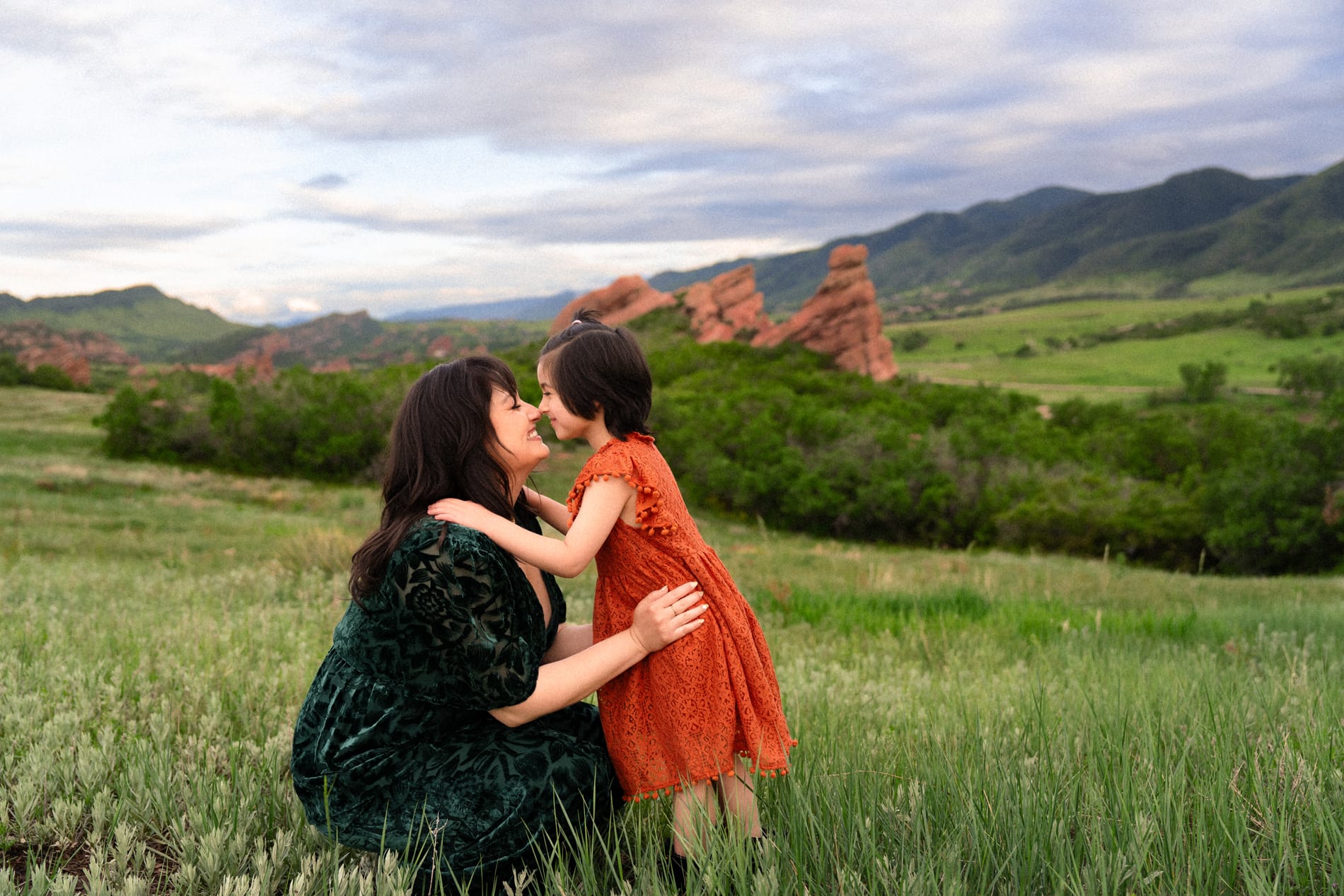 Family Photographer, a mother and daughter hold each other face to face in a green meadow