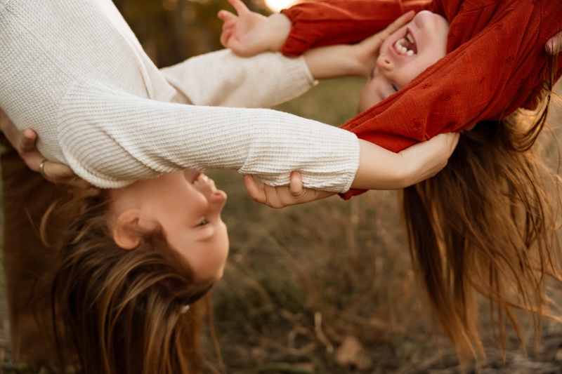 Family Photographer, two children are playfully held upside down and laughing